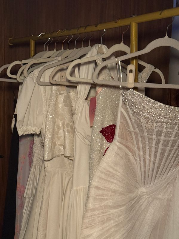 Vintage white bridal dresses with beading, pearls, and textured details displayed on a clothing rack at Something Blue.